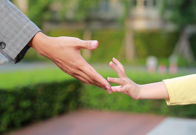 Mani della madre e della figlia di affari del primo piano che raggiungono l&#39;un l&#39;altro.