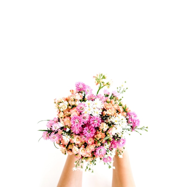 Mani della ragazza che tengono il mazzo dei fiori di campo su bianco