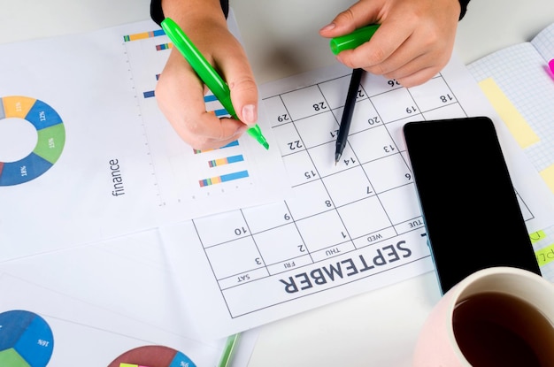 Mani della ragazza con il telefono cellulare con la scrittura del calendario e l'elenco dei lavori nel diario sulla scrivania