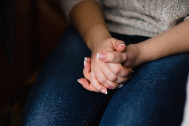 Mani della ragazza piegate con manicure francese bianco