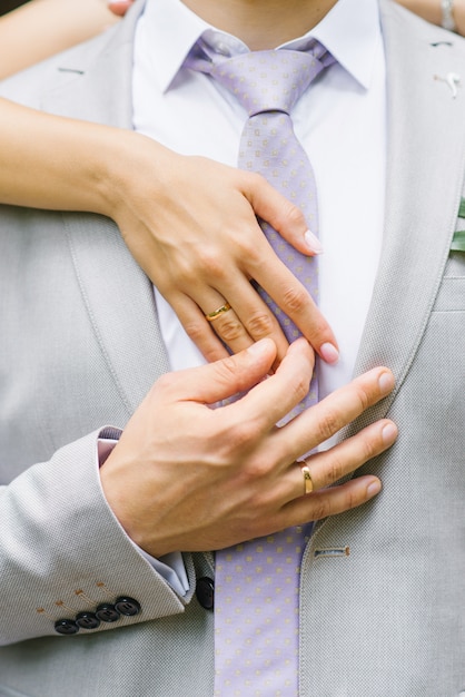 Mani della sposa e dello sposo con fedi nuziali.