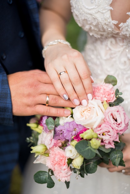 Mani della sposa e dello sposo con gli anelli sul mazzo di nozze. Concetto di matrimonio.