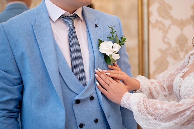 Mani della sposa e dello sposo con una decorazione di bouquet per la cerimonia di nozze