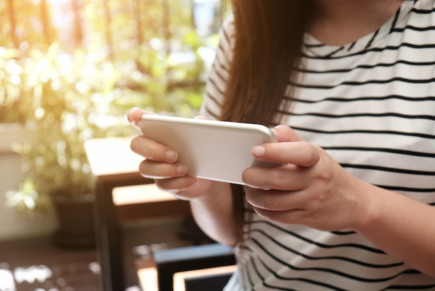 Mani delle donne che tengono il telefono cellulare a guardare i social media in uno smart phone. concetto di social network con smart phone