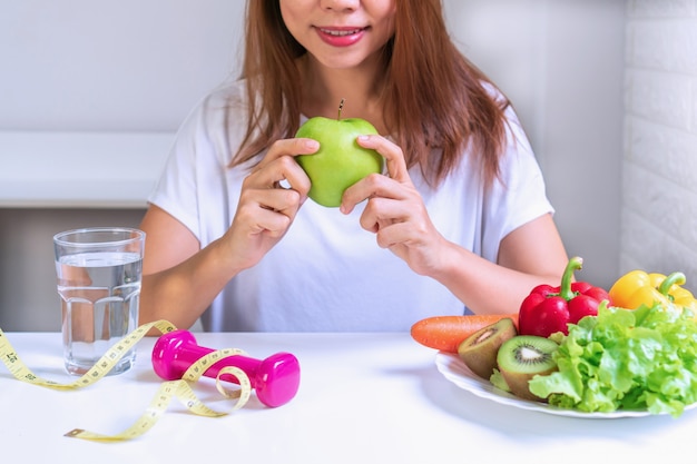 Mani delle donne che tengono mela verde con frutta, verdura, acqua. Selezione del concetto di cibo sano