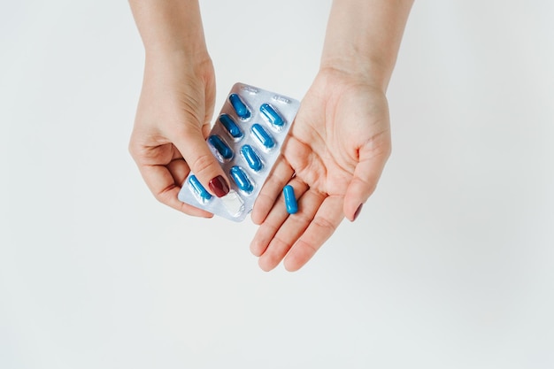 Mani delle donne con blister di pillole blu Sfondo bianco Concetto medico spazio di copia piatto