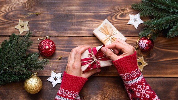 Mani delle donne in maglione lavorato a maglia che avvolge i regali