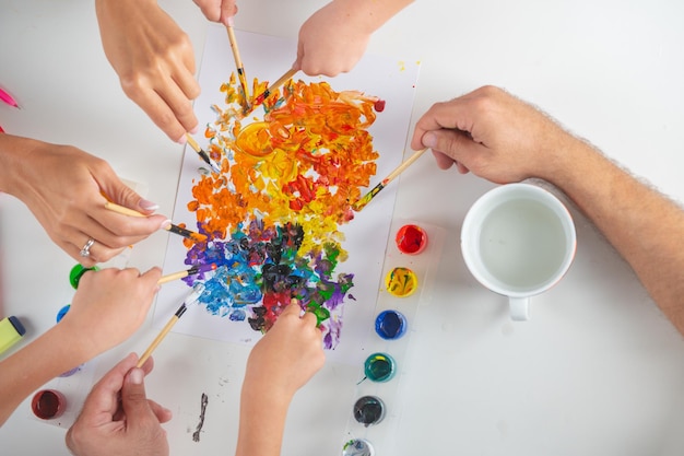 Mani delle madri dei padri con le mani dei bambini che dipingono e disegnano Vista dall'alto mani vecchie e giovani con forniture d'arte