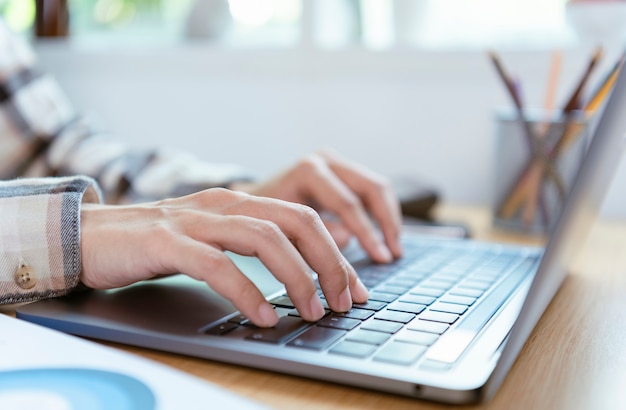 Mani delle persone di affari che digitano la tastiera del computer portatile sull'ufficio desktop.