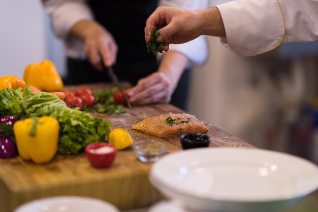 Mani dello chef che preparano filetti di salmone marinato da friggere nella cucina di un ristorante