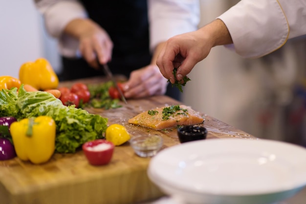 Mani dello chef che preparano filetti di salmone marinato da friggere nella cucina di un ristorante