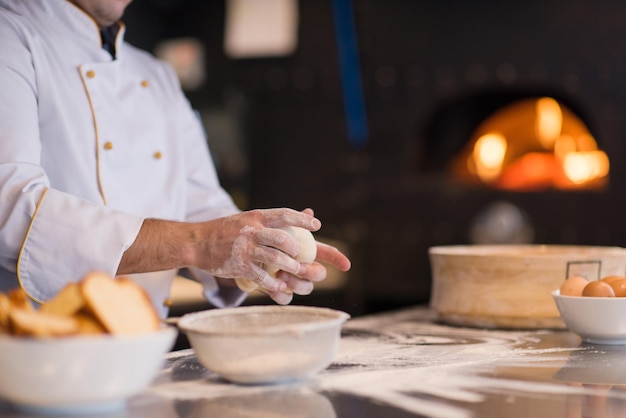 mani dello chef che preparano l'impasto per la pizza cosparso di primo piano della tavola di farina