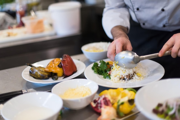 Mani dello chef che servono risotto alle verdure sulla cucina del ristorante