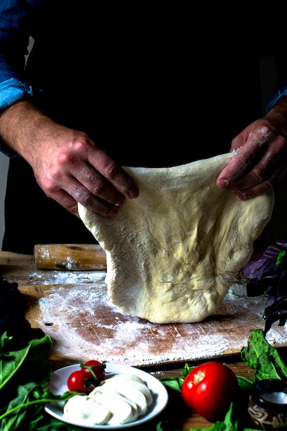 Mani dello chef chef italiano che cucina le mani dell'uomo della pizza che cucinano la pasta della pizza per pizza cuochi le mani