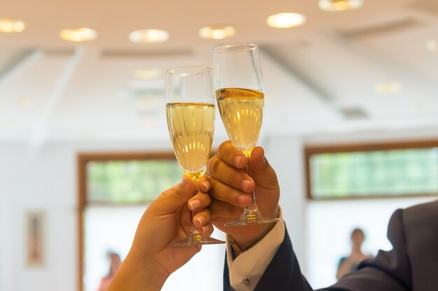 Mani dello sposo e della sposa con anelli che brindano con bicchieri di champagne a una celebrazione del matrimonio