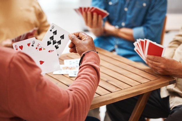 Mani di amici anziani o giochi di carte sul tavolo di legno in attività divertenti legami sociali o raduni Gruppo di uomini anziani che si divertono con le carte per il gioco del poker godendosi il tempo di gioco insieme a casa