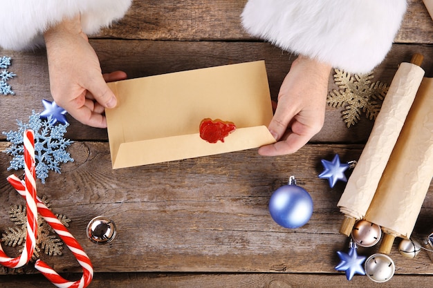 Mani di Babbo Natale con una busta su fondo in legno