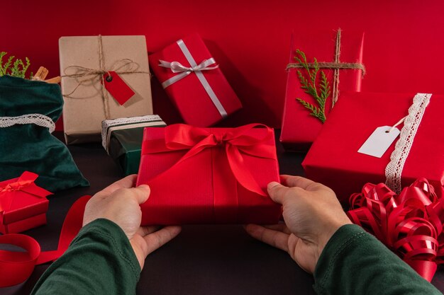 Mani di concetto di Natale che tengono la decorazione di Natale sopra il tiro e la vista orizzontale del fondo nero