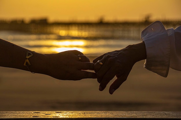 mani di coppia al tramonto sulla spiaggia