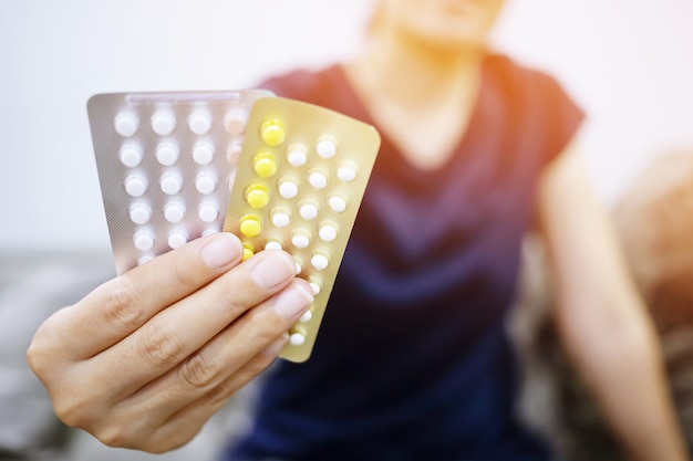 Mani di donna apertura pillole anticoncezionali in mano. Assunzione di pillola contraccettiva.