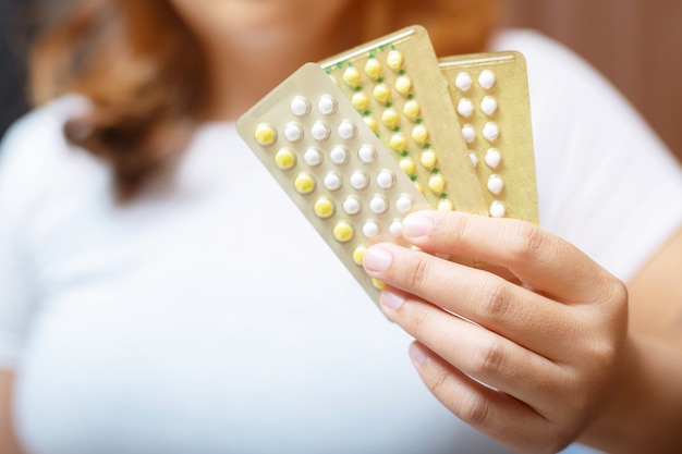 Mani di donna apertura pillole anticoncezionali in mano. Mangiare pillola contraccettiva.