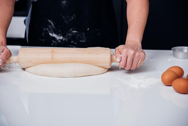 Mani di donna che fanno la pasta con il rotolamento del legno