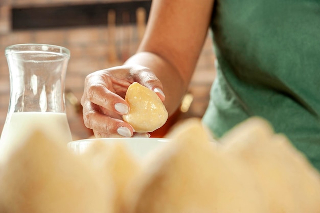 Mani di donna che impanano la crocchetta brasiliana coxinha de frango con pangrattato su un tavolo da cucina in legno