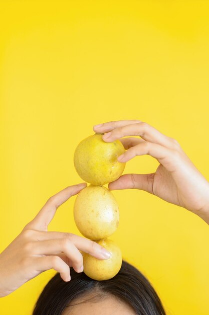 Mani di donna che tengono i limoni sulla testa sfondo giallo brillante con spazio di copia