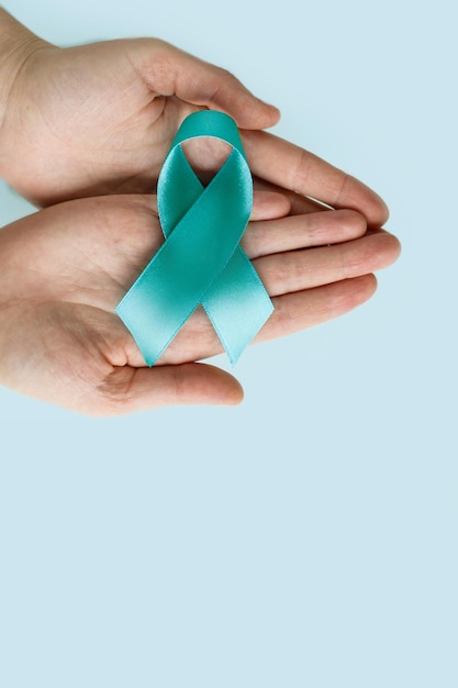 Mani di donna che tengono il nastro Teal simbolico per il cancro cervicale cancro ovarico cancro ginecologico