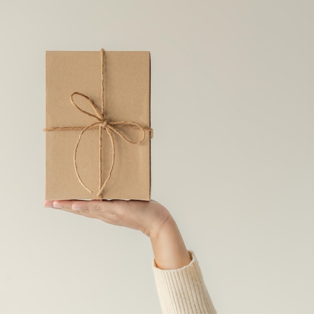 Mani di donna che tengono scatola regalo con un fiocco di nastro Concetto minimalista di fare un regalo