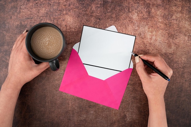 Mani di donna con busta di carta bianca penna e tazza di caffè su sfondo di legno Imprenditrice bere e scrivere un messaggio cruciale sulla lettera aziendale