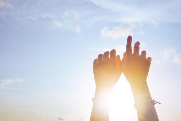 Mani di donna contro il cielo blu e il sole