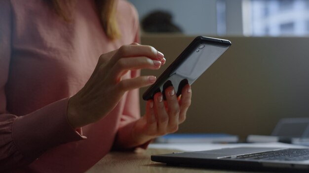 Mani di donna d'affari irriconoscibili che utilizzano lo smartphone in ufficio Lavoratore aziendale che scorre la pagina Internet sul telefono cellulare sul posto di lavoro Donna d'affari braccia messaggio di testo online sul cellulare