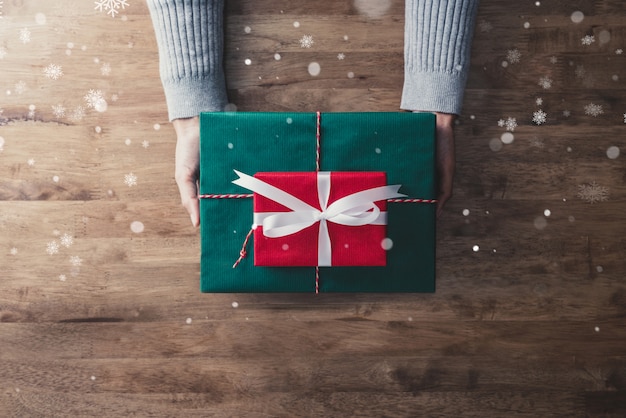 Mani di donna in maglione grigio sul tavolo in legno givin Scatole regalo di Natale