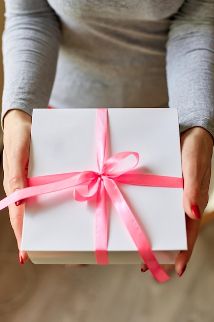 Mani di donna in possesso di una scatola regalo bianca con nastro rosa Mani femminili in possesso di confezione regalo Natale hew anno compleanno San Valentino concetto xAday Copia spazio