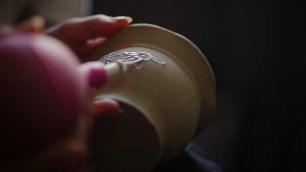 Mani di donna in primo piano che disegna su una pentola in studio Artista femminile non riconosciuta che fa ornamenti su un prodotto in argilla in laboratorio artigiano sconosciuto che decora una pentola di argilla in ceramica