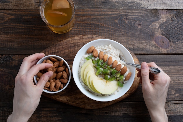 mani di donne a colazione, farina d&#39;avena con mandorle e mele, noci, frutti di bosco, composta.