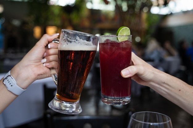 Mani di donne che brindano con un barattolo di birra e un bicchiere di sangria. Bevande alcoliche, concetto di celebrazione della festa