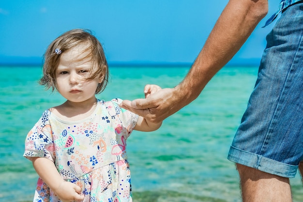 Mani di felice genitore e bambino in mare Grecia sfondo