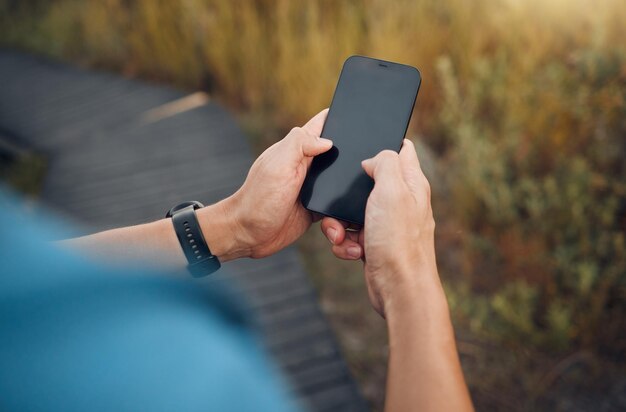 Mani di fitness e schermo del telefono mockup del corridore che si esercita nella natura Tracciamento digitale della tecnologia e uomo che utilizza lo smartphone facendo allenamento allenamento e corsa in montagna con tecnologia intelligente