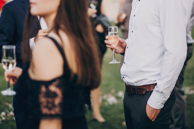 Mani di gente alla moda che tifa con bicchieri di champagne ricevimento di nozze di lusso ricchi ospiti di celebrazione che brindano alla festa di celebrazione di lusso di natale