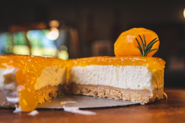 Mani di giovane chef fornaio che taglia una fetta di cheesecake al mango