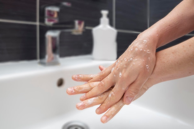 Mani di lavaggio della donna con sapone