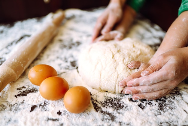 Mani di madre e figlio che impastano insieme una pasta Le mani della madre e del bambino preparano l'impasto.