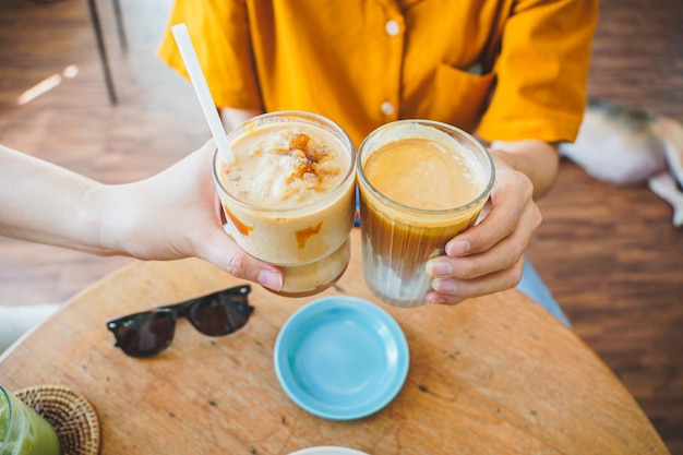 Mani di ragazze adolescenti che tengono e bevono caffè ghiacciato insieme al caffè.