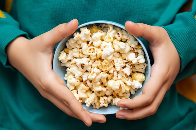 Mani di ragazzi e una ciotola di primo piano di popcorn