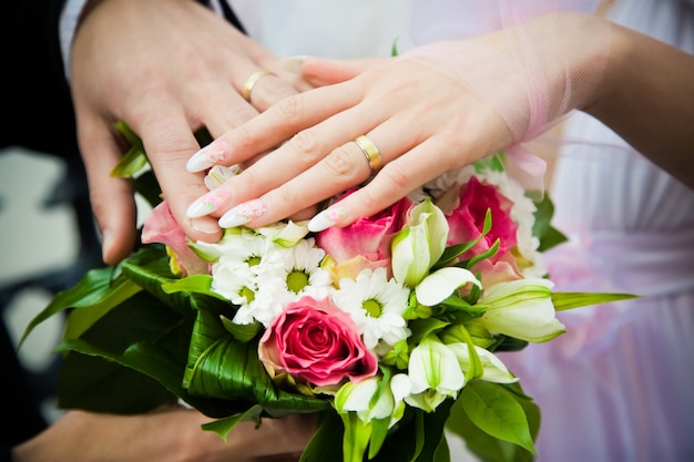 Mani di sposi con bouquet da sposa