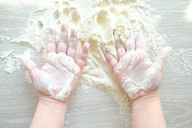 Mani di un bambino nella farina. Il bambino sta cucinando.