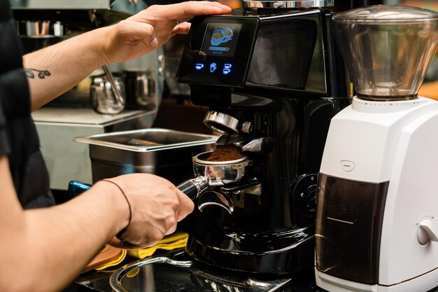 Mani di un barista che prepara il caffè in una macchina per caffè espresso.