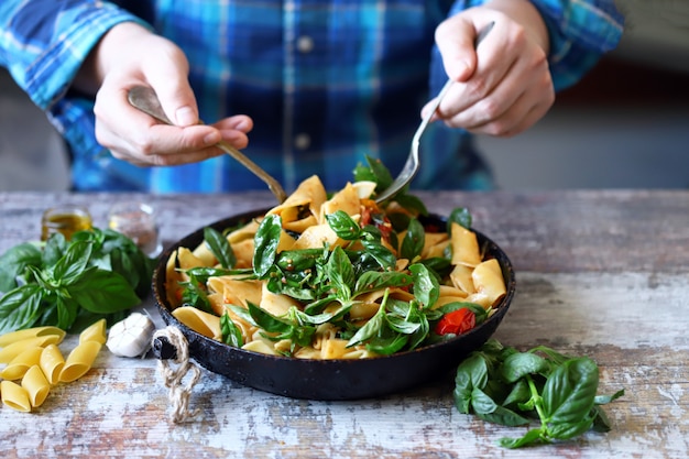 Mani di un cuoco unico che cucina l'insalata di pasta